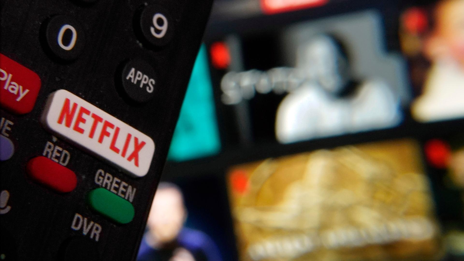 Ein eigener Netflix-Schaler auf der Fernbedienung, im Hintergrund ein TV-Bildschirm Ein eigener Netflix-Schaler auf der Fernbedienung, im Hintergrund ein TV-Bildschirm