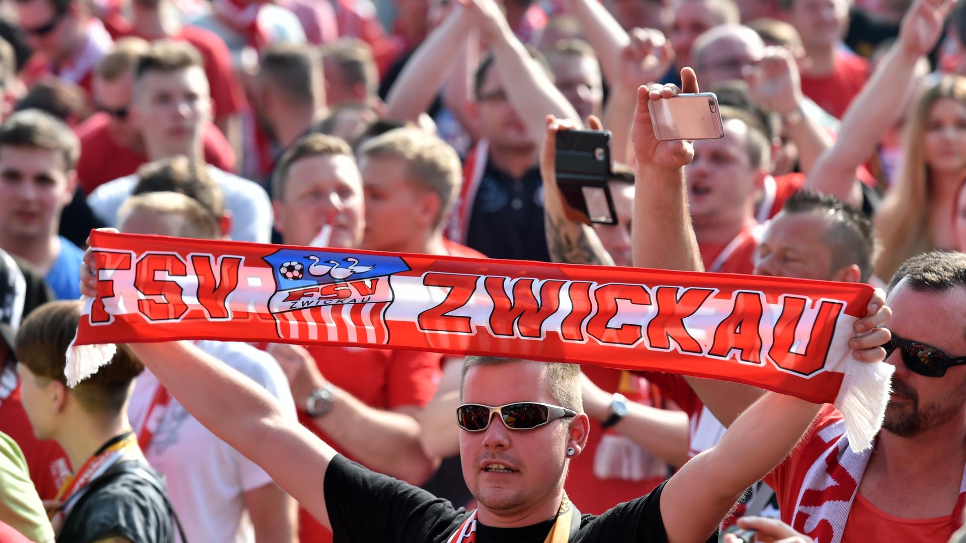 Fußballfans des FSV Zwickau. Ein Fan mit Sonnenbrille hält einen Schal mit der Aufschrift "FSV Zwickau" hoch. Fußballfans des FSV Zwickau. Ein Fan mit Sonnenbrille hält einen Schal mit der Aufschrift "FSV Zwickau" hoch.