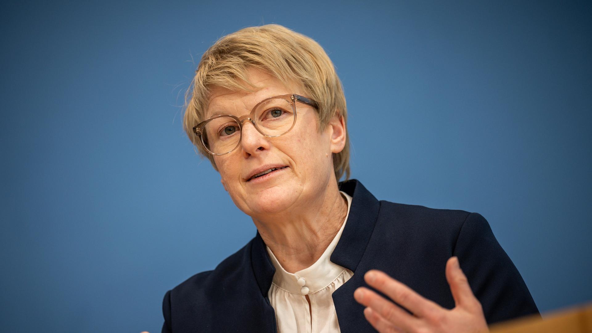 Veronika Grimm spricht und gestikuliert vor blauem Hintergrund. Veronika Grimm spricht und gestikuliert vor blauem Hintergrund.