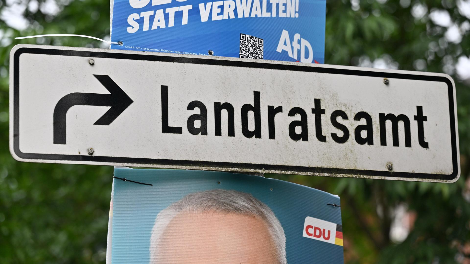 Neben einem Wegweiser zum Landratsamt hängen Plakate mit Fotos der Kandidaten. Neben einem Wegweiser zum Landratsamt hängen Plakate mit Fotos der Kandidaten.