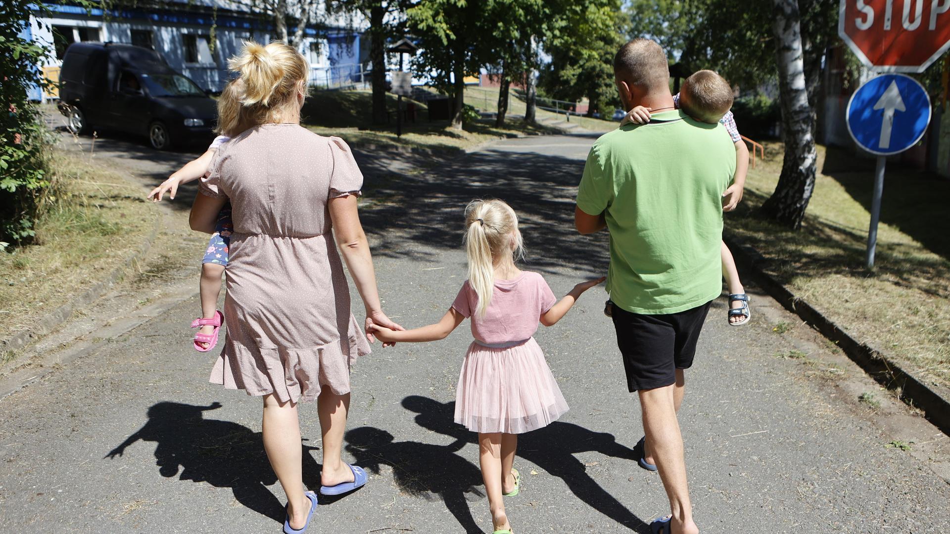 Eine ukrainische Familie mit drei Kindern geht eine Straße entlang. Eine ukrainische Familie mit drei Kindern geht eine Straße entlang.