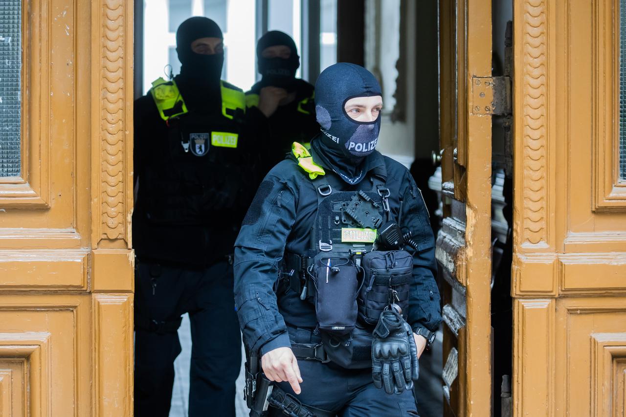 Polizisten kommen bei einer Hausdurchsuchung in Berlin-Kreuzberg aus einem Gebäude. Polizisten kommen bei einer Hausdurchsuchung in Berlin-Kreuzberg aus einem Gebäude.