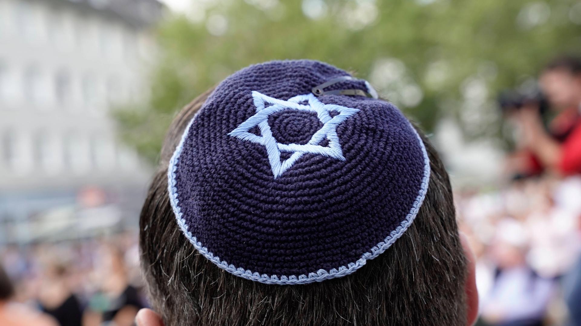 Ein Mann trägt eine leuchtend blaue Kippa auf dem Hinterkopf. Auf der Kippa ist ein hellblauer Davidstern abgebildet. Ein Mann trägt eine leuchtend blaue Kippa auf dem Hinterkopf. Auf der Kippa ist ein hellblauer Davidstern abgebildet.