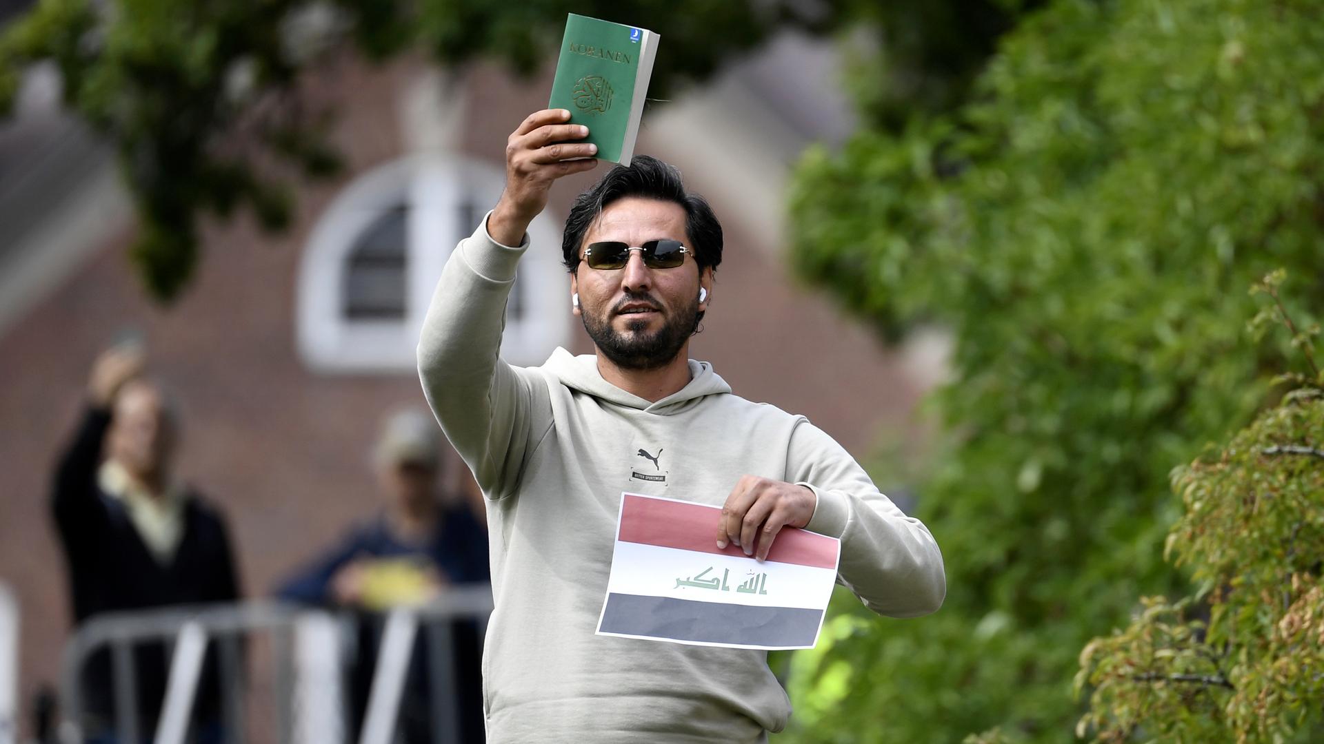 Ein Mann hält eine Kopie des Korans hoch. Ein Mann hält eine Kopie des Korans hoch.