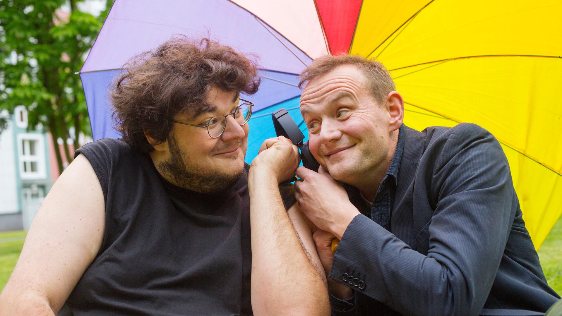 Axel Rahnisch und Devid Striesow unter einem regenbogenfarbenen Regenschirm Axel Rahnisch und Devid Striesow unter einem regenbogenfarbenen Regenschirm