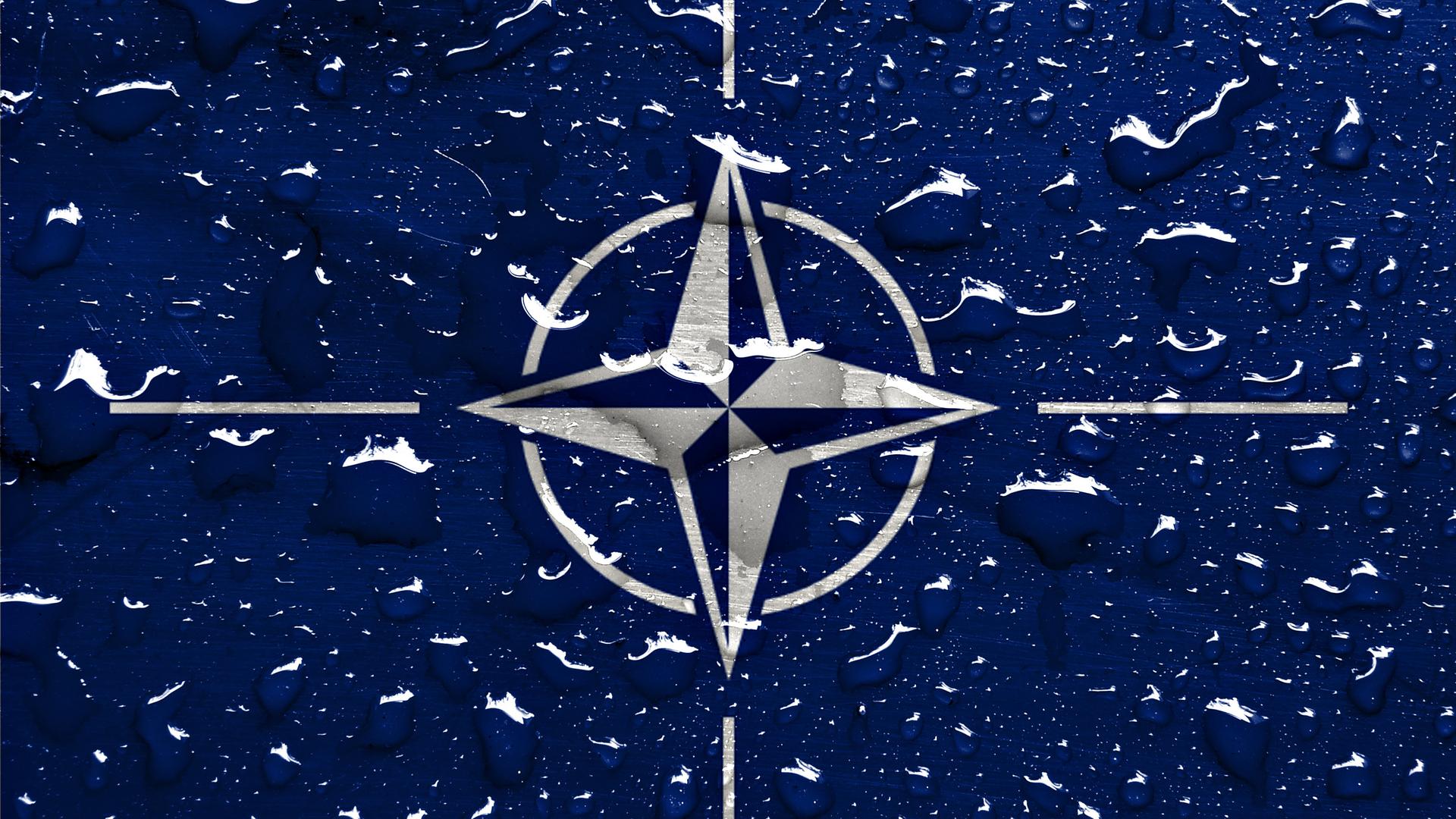 Auf dem NATO-Logo sind Regentropfen zu sehen. Auf dem NATO-Logo sind Regentropfen zu sehen.