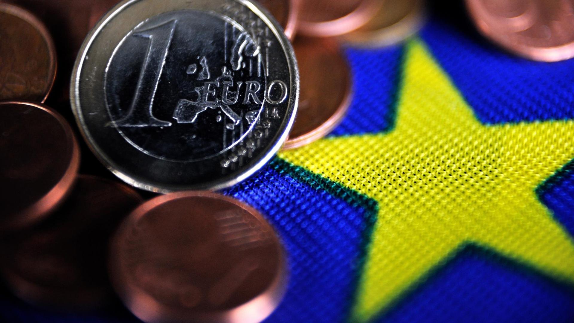 Euro-Münzen liegen auf einer EU-Flagge Euro-Münzen liegen auf einer EU-Flagge