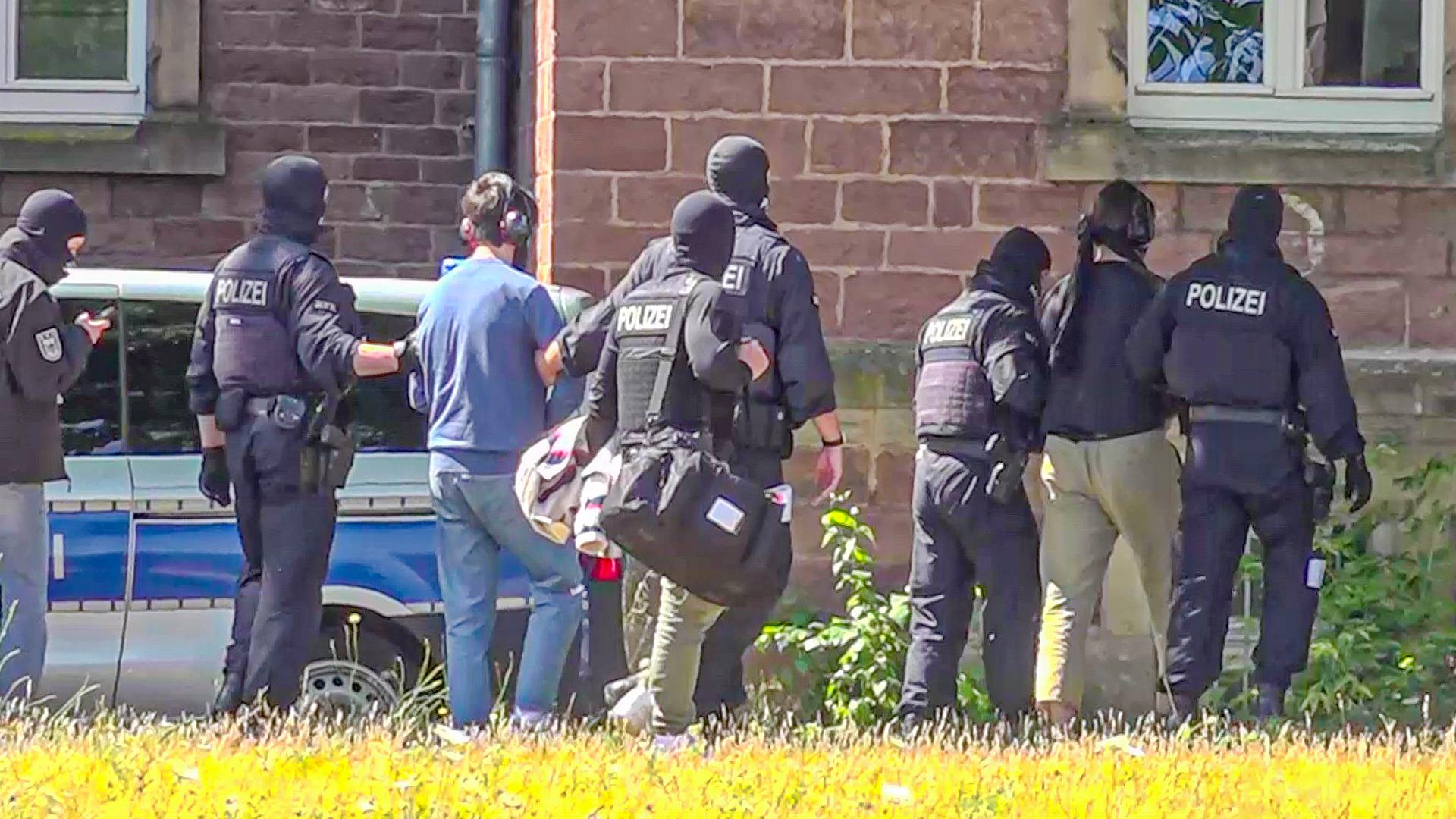 Polizisten mit Sturmhauben führen zwei Männer ab Polizisten mit Sturmhauben führen zwei Männer ab
