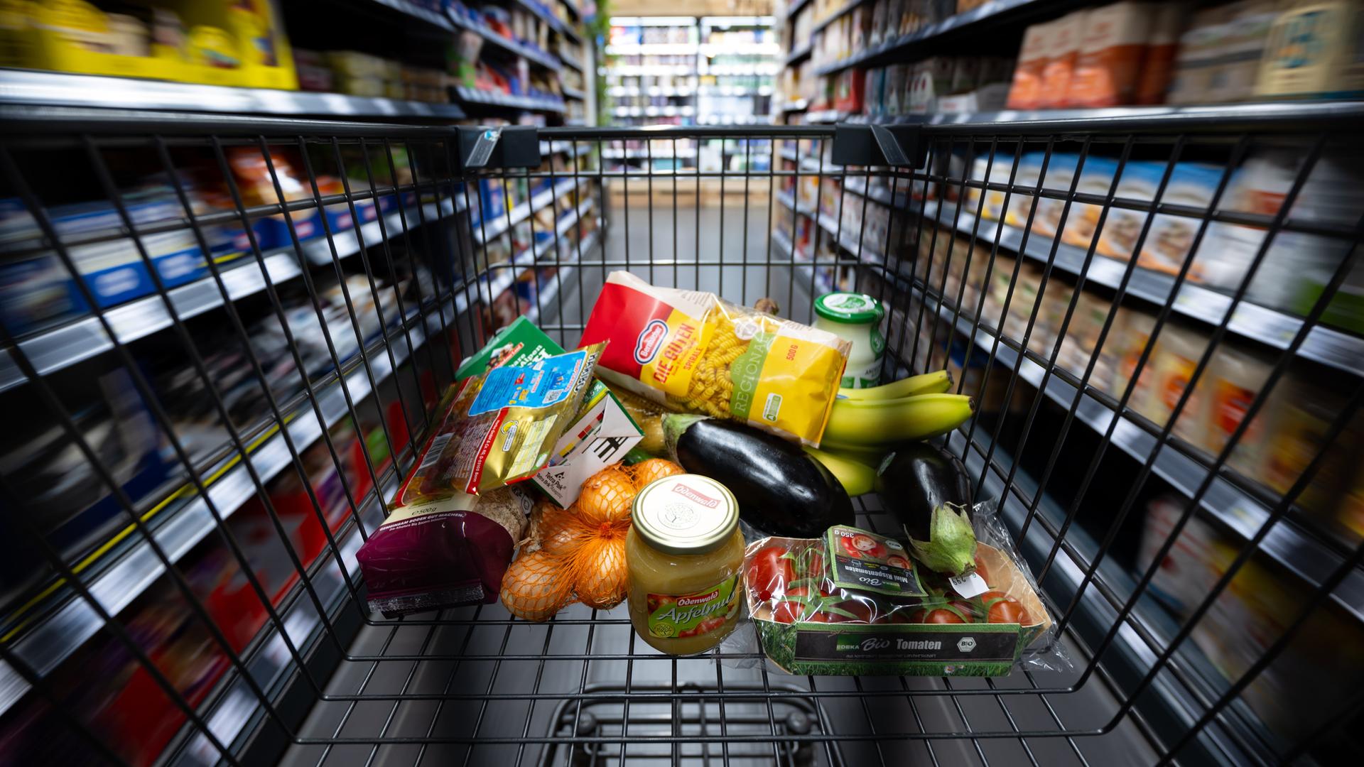 In einem Supermarkt liegen verschiedene Lebensmittel in einem Einkaufswagen. In einem Supermarkt liegen verschiedene Lebensmittel in einem Einkaufswagen.