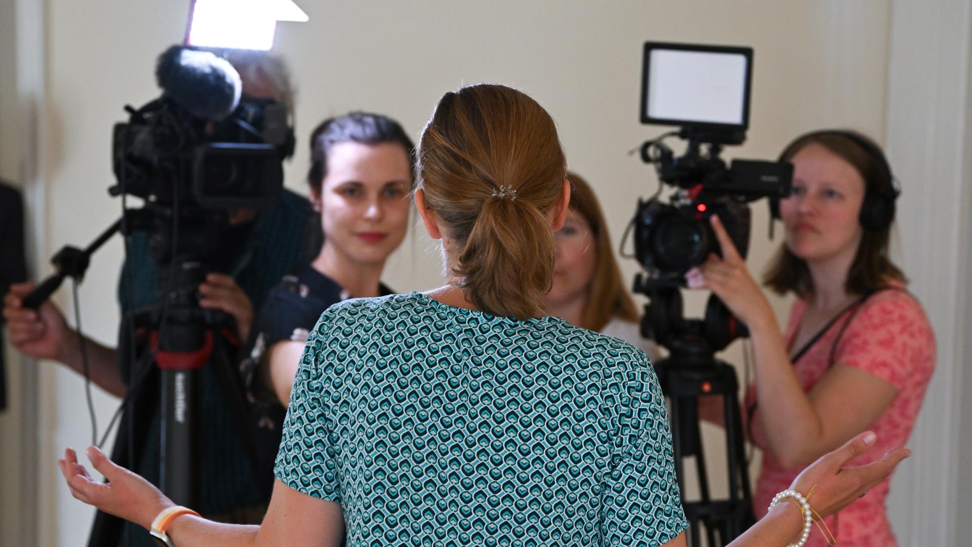 Eine Klägerin äußert sich am 26. Juni 2023 im Flur des Landgerichts Mainz im Anschluss an die Verhandlung um einen möglichen Impfschaden im Zusammenhang mit dem Corona-Vakzin von Astrazeneca vor TV-Kameras Eine Klägerin äußert sich am 26. Juni 2023 im Flur des Landgerichts Mainz im Anschluss an die Verhandlung um einen möglichen Impfschaden im Zusammenhang mit dem Corona-Vakzin von Astrazeneca vor TV-Kameras
