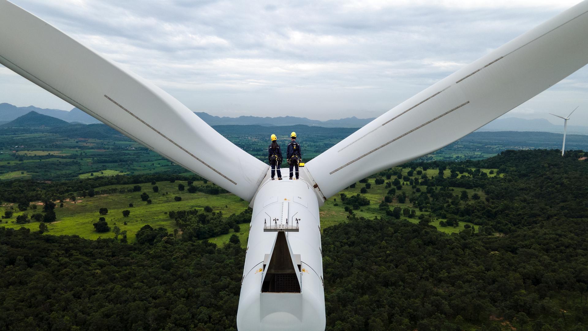 Zwei Arbeiter stehen auf einer Windmühle und blicken in die Ferne. Zwei Arbeiter stehen auf einer Windmühle und blicken in die Ferne.