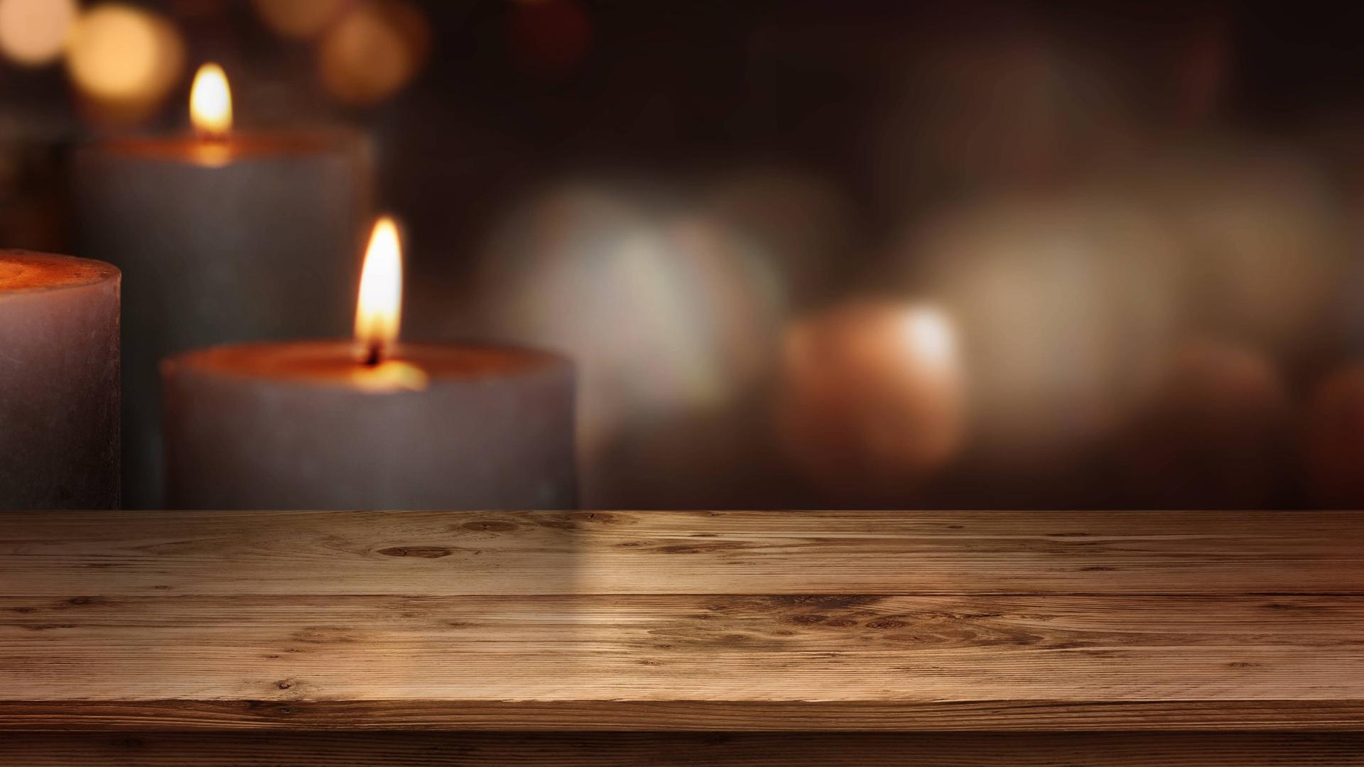 Holztisch mit Kerzen vor dunklem Hintergrund Holztisch mit Kerzen vor dunklem Hintergrund