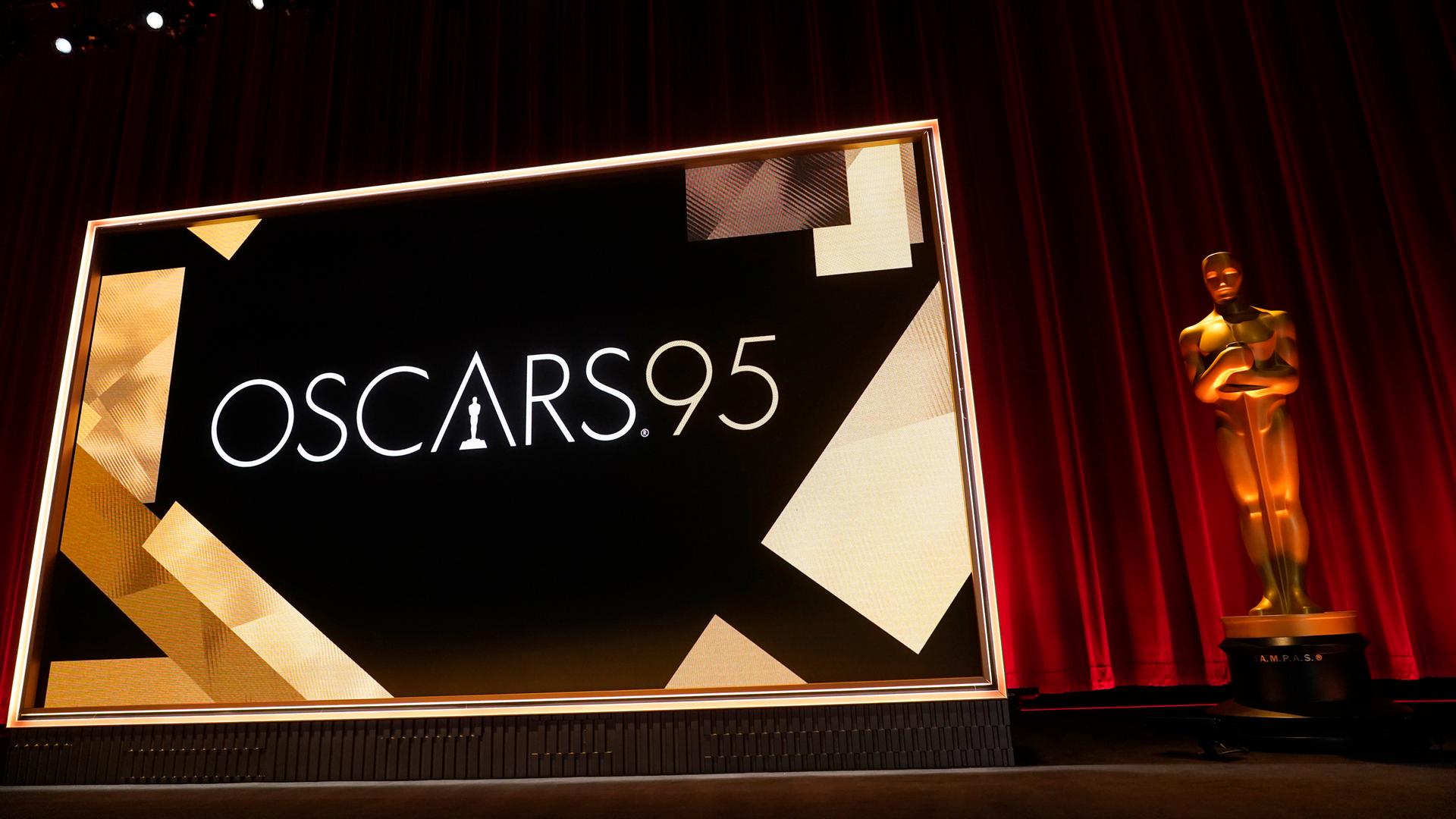 Die Bühne der 95. Oscar-Verleihungen. Vor einem Roten Samtvorhang steht eine große goldene Oscar-Figur. Daneben eine Leinwand. Die Bühne der 95. Oscar-Verleihungen. Vor einem Roten Samtvorhang steht eine große goldene Oscar-Figur. Daneben eine Leinwand.