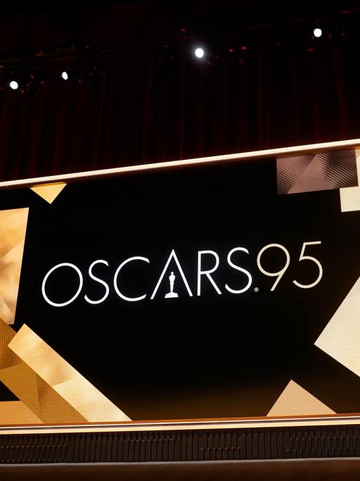 Die Bühne der 95. Oscar-Verleihungen. Vor einem Roten Samtvorhang steht eine große goldene Oscar-Figur. Daneben eine Leinwand.