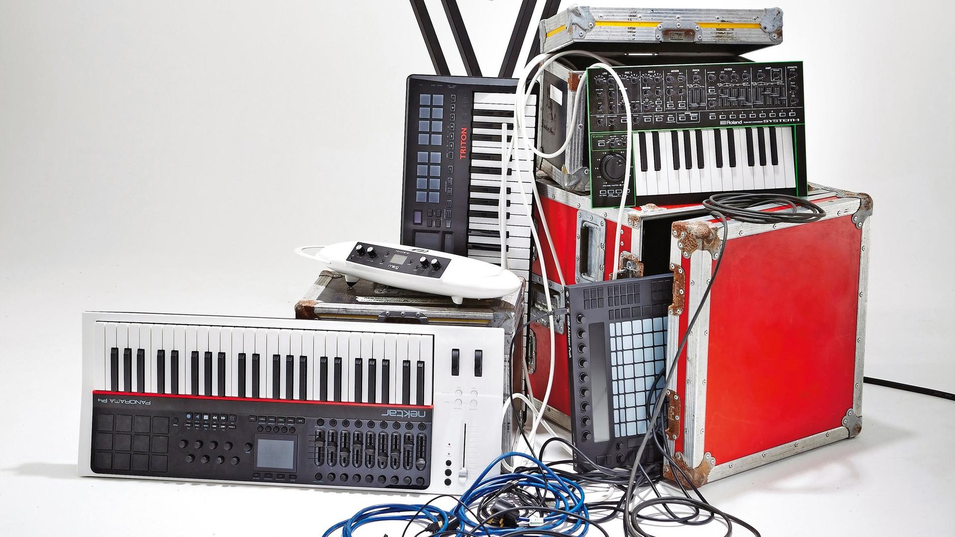 Eine Auswahl an Audio- und Musikequipment, darunter Synthesizer, Keyboards und Kabel. Eine Auswahl an Audio- und Musikequipment, darunter Synthesizer, Keyboards und Kabel.