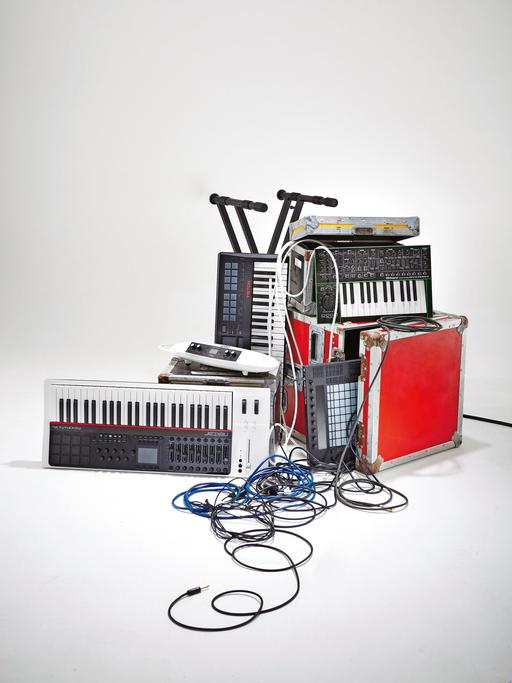 Eine Auswahl an Audio- und Musikequipment, darunter Synthesizer, Keyboards und Kabel.