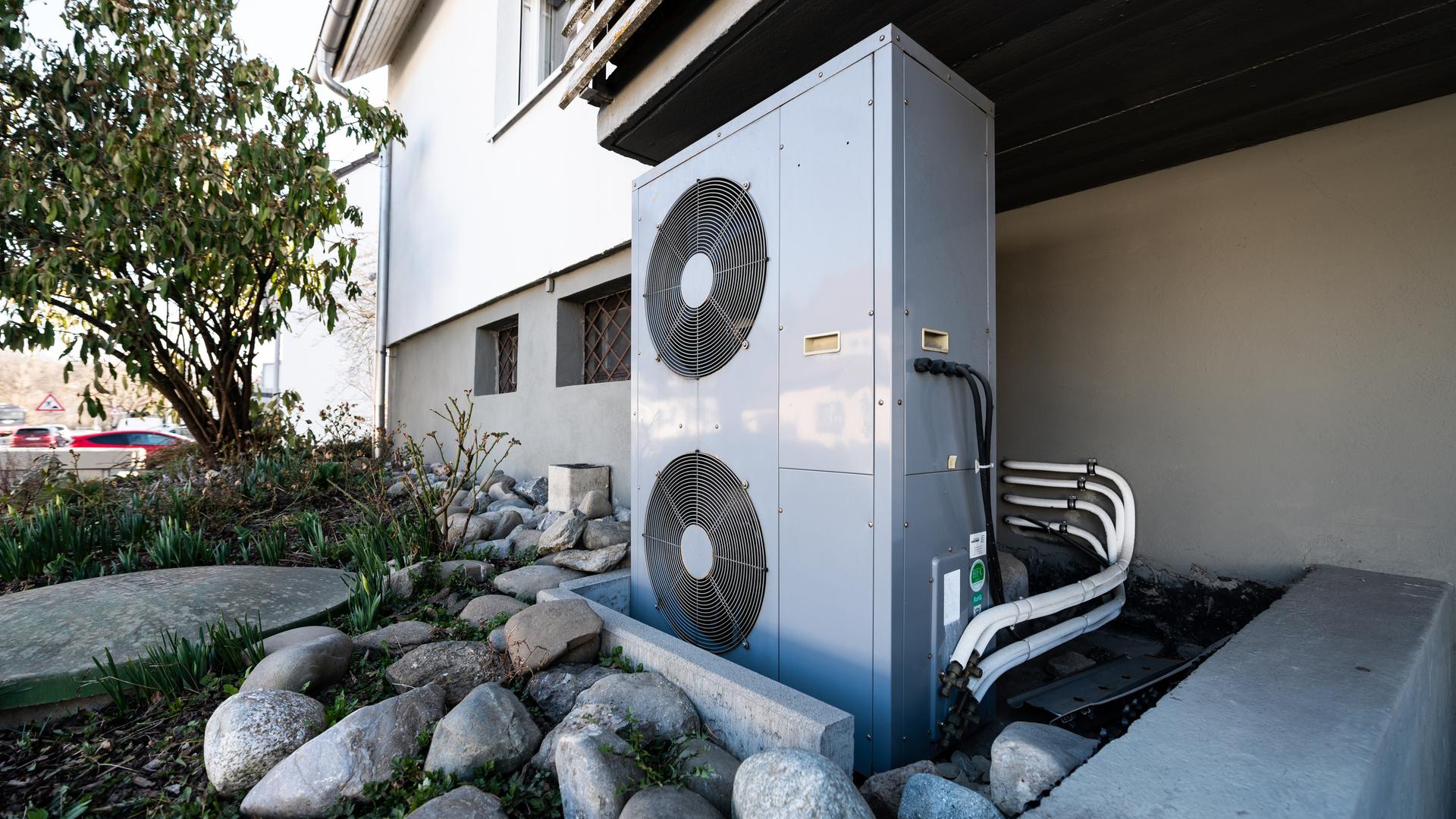 Die Lüftungsanlage einer Wärmepumpe steht vor einem Wohnhaus. Die Lüftungsanlage einer Wärmepumpe steht vor einem Wohnhaus.