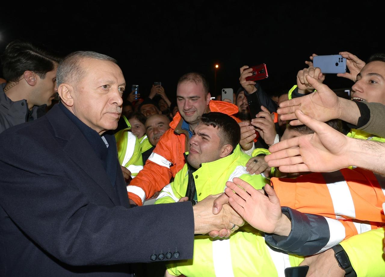 Der türkische Präsident Erdogan bei einem Besuch im Erdbebengebiet. Viele Menschen strecken ihm ihre Hände entgegen.