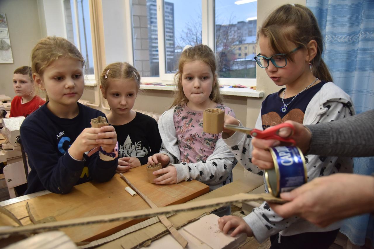 Vier Kinder stehen um einen Schultisch und basteln. Vier Kinder stehen um einen Schultisch und basteln.