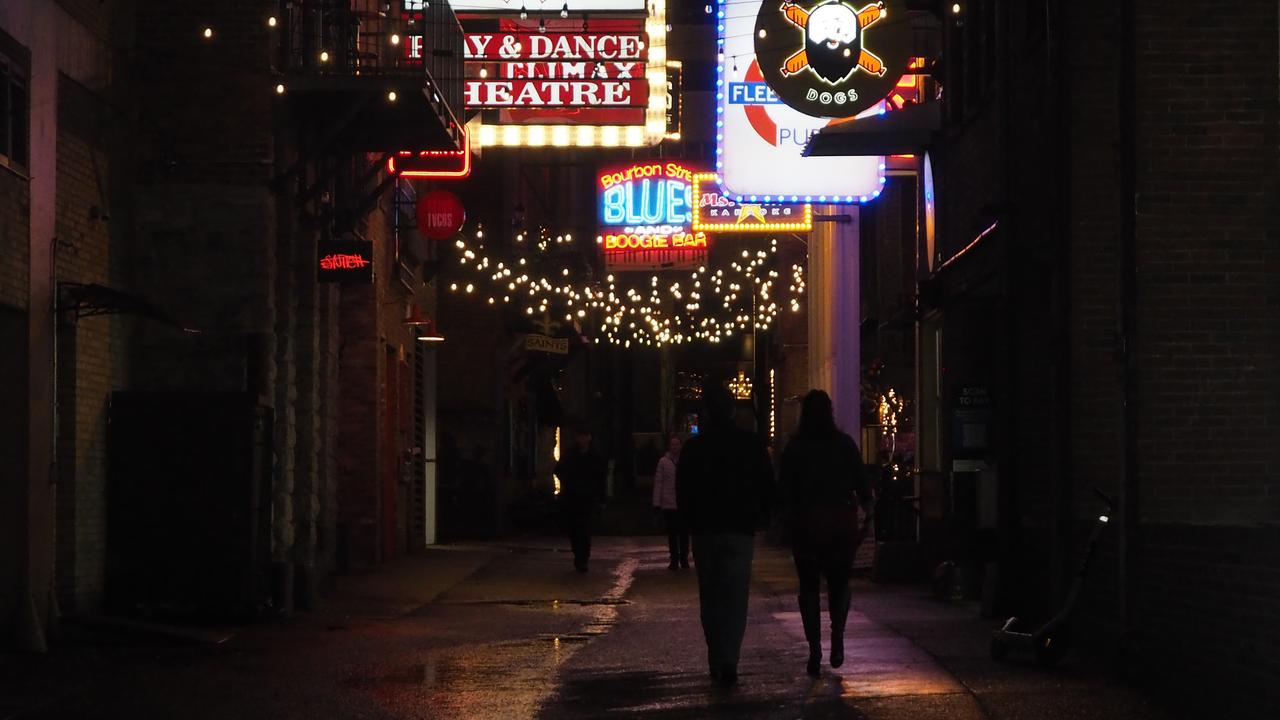 Nachtszene in Nashville. Zwei Personen gehen durch eine mit Neonzeichen beleuchtete Gasse.