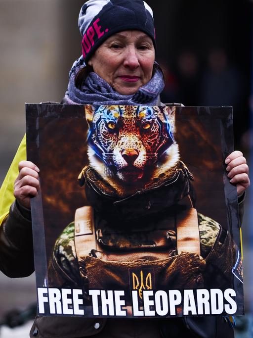 Eine Demonstrantin hält das Bild eines Leoparden hoch mit der Aufschrift "Lass die Leoparden frei".  