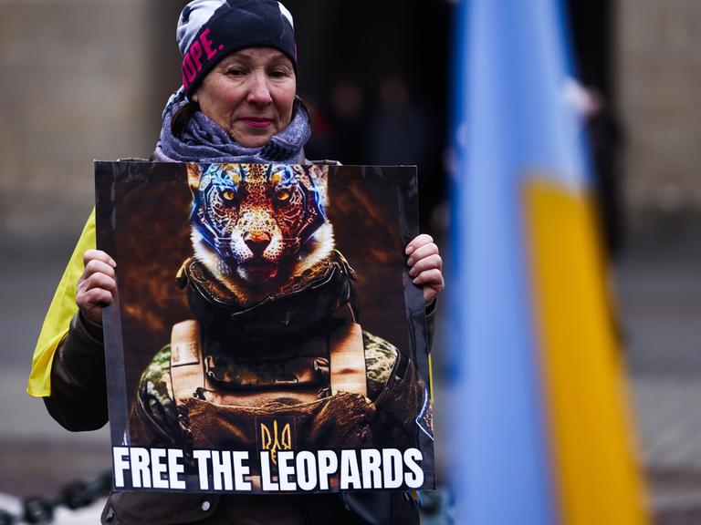 Eine Demonstrantin hält das Bild eines Leoparden hoch mit der Aufschrift "Lass die Leoparden frei".  