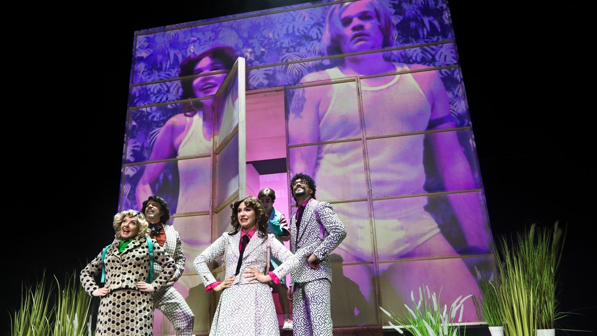 Zwei Frauen, drei Männer in 80er-Jahren-Klamotten stehen affektiert auf der Bühne.