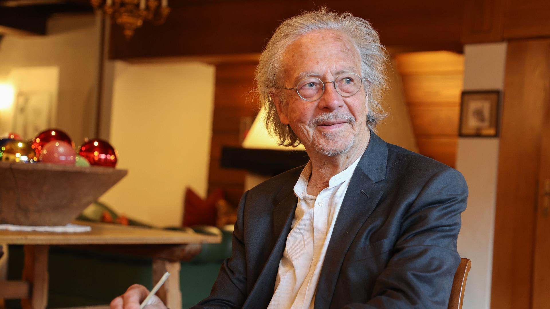 Autor Peter Handke sitzt bei einem Kartenspiel an einem Tisch und hält einen Stift in der Hand. Autor Peter Handke sitzt bei einem Kartenspiel an einem Tisch und hält einen Stift in der Hand.