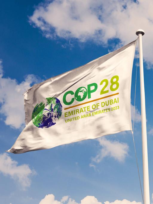 Eine weiß Fahne mit dem Logo der Weltklimakonferenz COP28 flattert im Wind.
