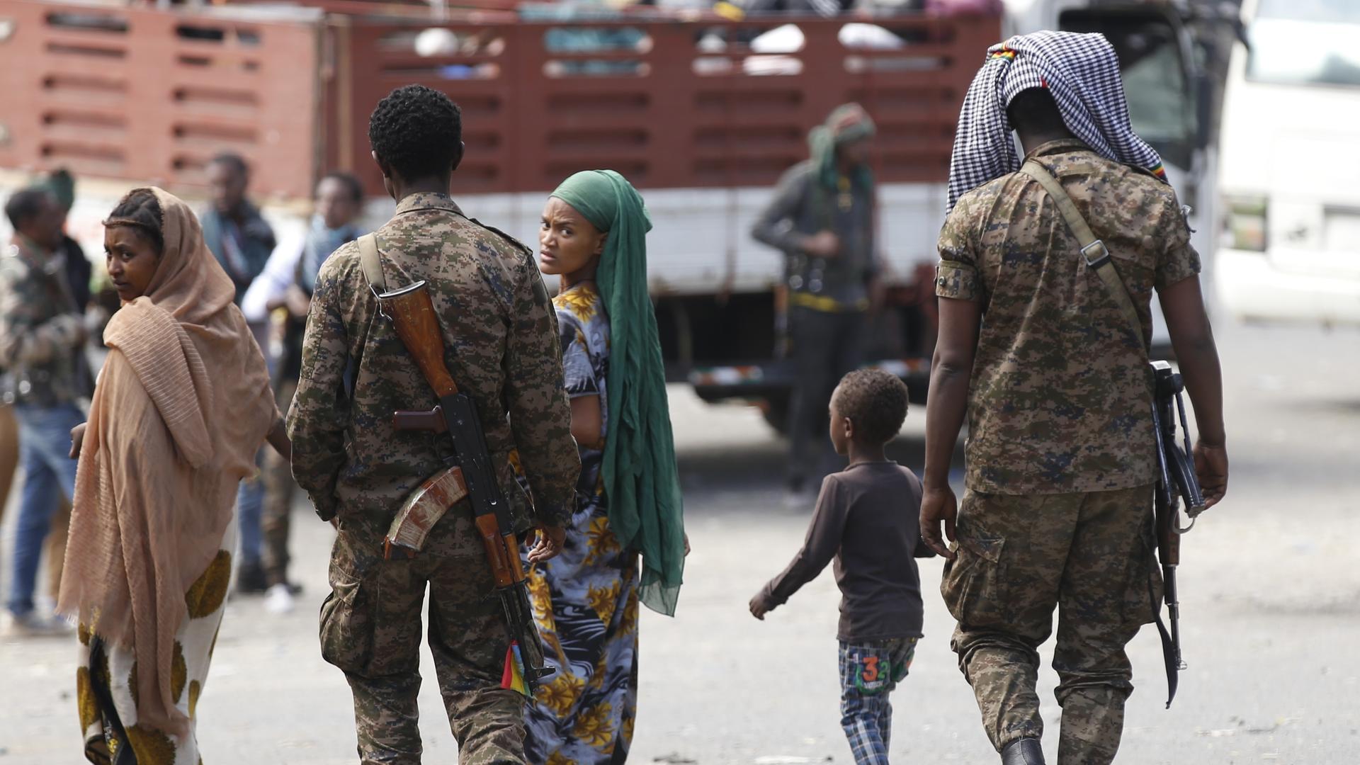 Äthiopische Militärangehörige laufen gemeinsam mit zwei Frauen und einem Kind eine Straße entlang. Eine der Frauen blickt sorgenvoll in die Kamera. Äthiopische Militärangehörige laufen gemeinsam mit zwei Frauen und einem Kind eine Straße entlang. Eine der Frauen blickt sorgenvoll in die Kamera.
