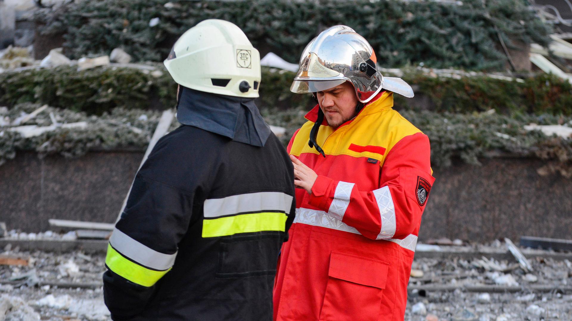 Ein Polizist und ein Feuerwehrmann stehen nach einem russischen Raketenangriff auf die ukrainische Hauptstadt Kiew am 31. Dezember 2022 vor Trümmern eines Hauses. Ein Polizist und ein Feuerwehrmann stehen nach einem russischen Raketenangriff auf die ukrainische Hauptstadt Kiew am 31. Dezember 2022 vor Trümmern eines Hauses.