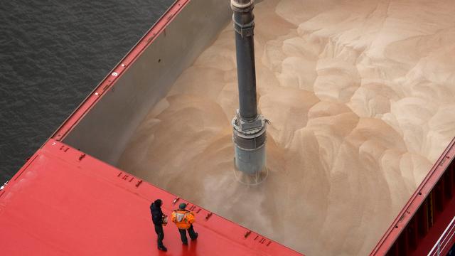  Getreideanlieferung im Hamburger Hafen. Zwei Männer stehen auf einem Schiff, das mit Getreide beladen ist.