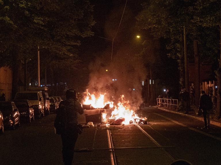 Am Vorabend des "Tag X" anlässlich des Antifa Ost Prozesses zogen mehrere Hundert Menschen aus der linksautonomen und linksextremen Szene durch den Leipziger Stadtteil Connewitz. Mülleimer brennen auf der Mitte einer Straße. 