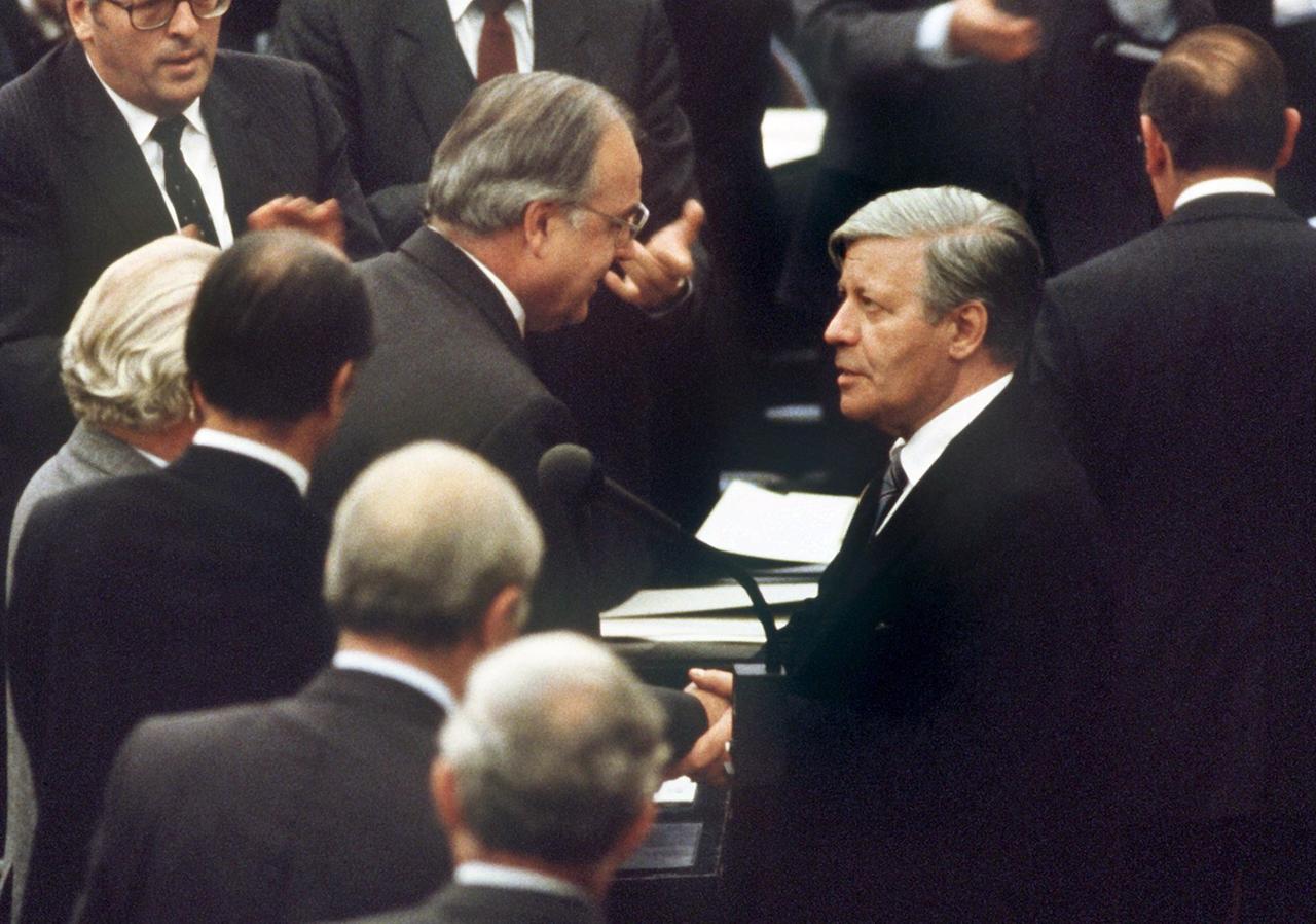 Der gestürzte Bundeskanzler Helmut Schmidt (r., SPD) beglückwünscht am 1.10.1982 seinen Nachfolger Helmut Kohl (M.) zu dessen Wahl.