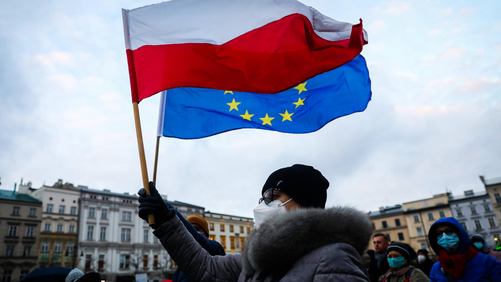 Eine Frau hält in Krakau in Polen bei Protesten gegen das geplante Mediengesetz eine polnische und eine EU-Flagge in der Hand Eine Frau hält in Krakau in Polen bei Protesten gegen das geplante Mediengesetz eine polnische und eine EU-Flagge in der Hand