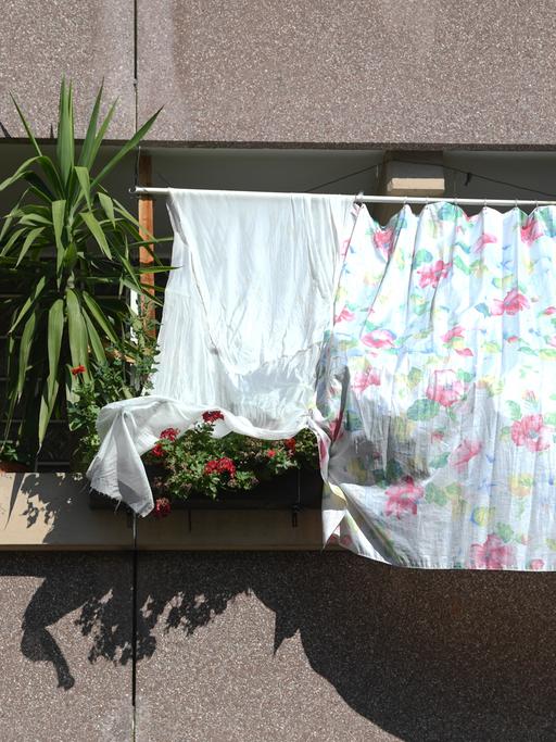 Mit auf dem Balkon gespannten Tüchern schützen Bewohner notdürftig ihre Wohnung  vor der heißen Sonne. 