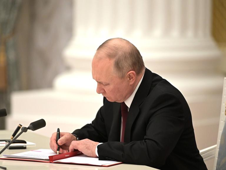 Der russische Präsident Wladimir Putin unterzeichnet am 21. Februar 2022 ein Dokument
