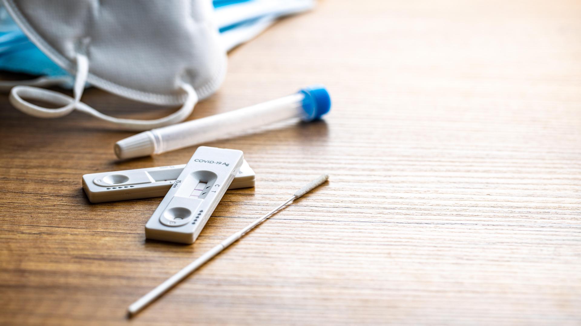 Eine Coronatestkassette mit zwei roten Streifen liegt auf einem Tisch Eine Coronatestkassette mit zwei roten Streifen liegt auf einem Tisch