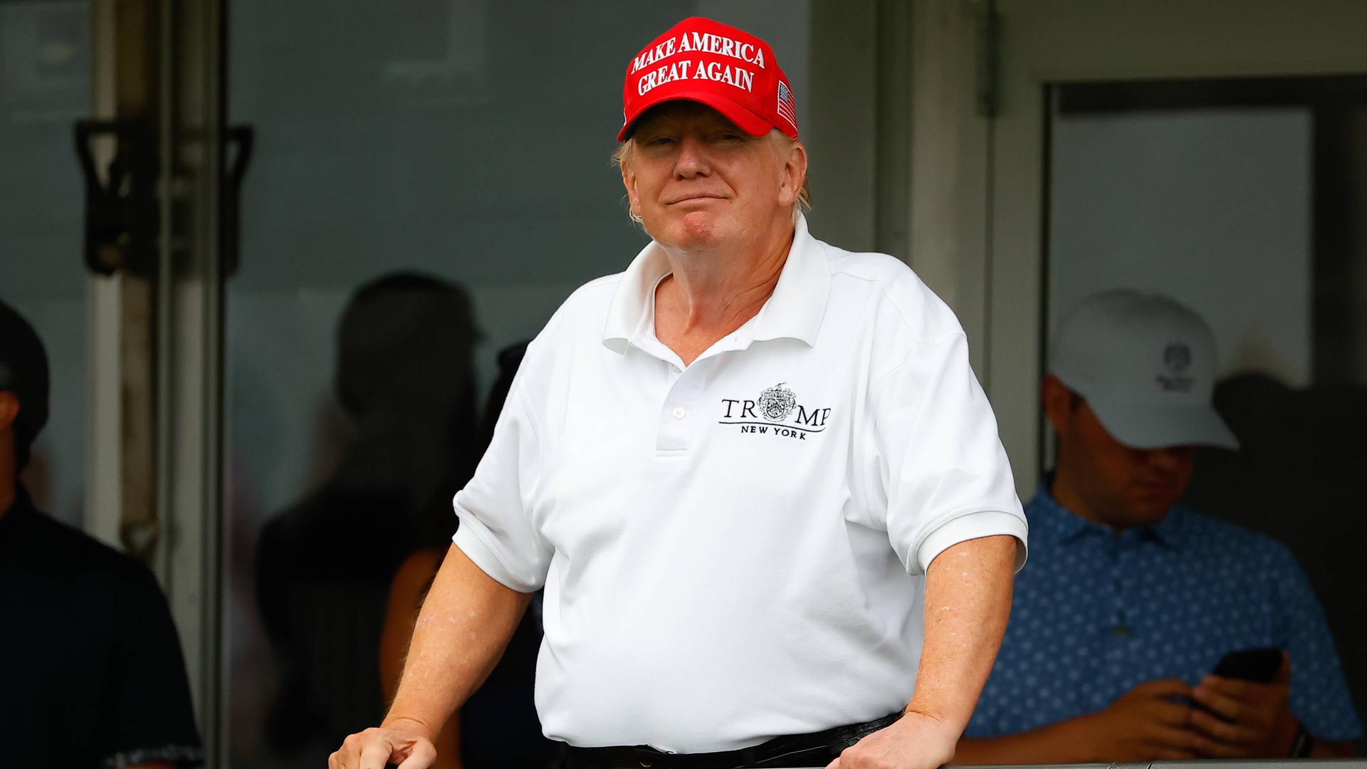 Donald Trump lächelt von einem Balkon im Trump National Golf Club in New Jersey.