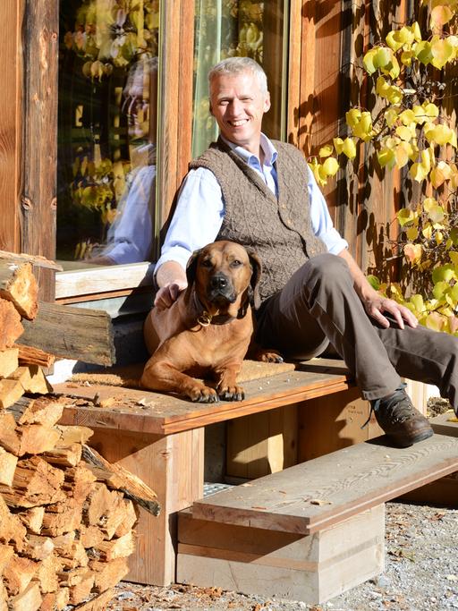 Förster und Unternehmer Erwin Thoma sitzt mit seinem Hund vor seinem Haus.