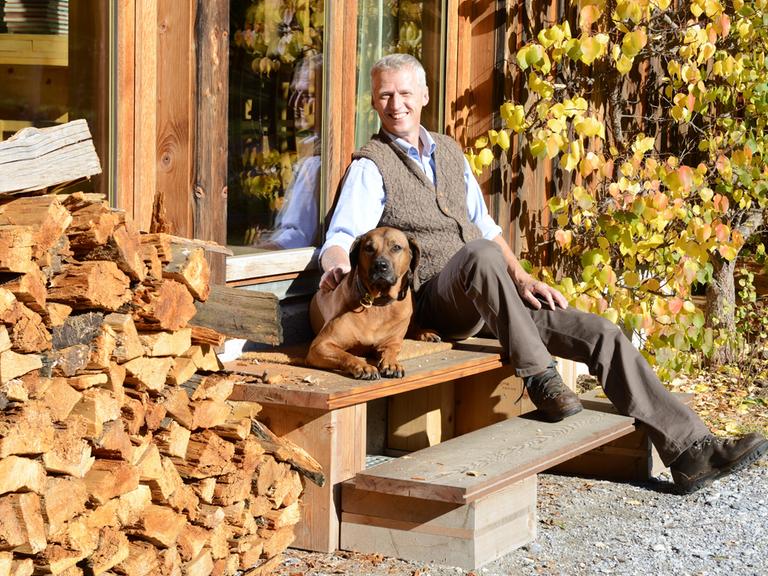 Förster und Unternehmer Erwin Thoma sitzt mit seinem Hund vor seinem Haus.