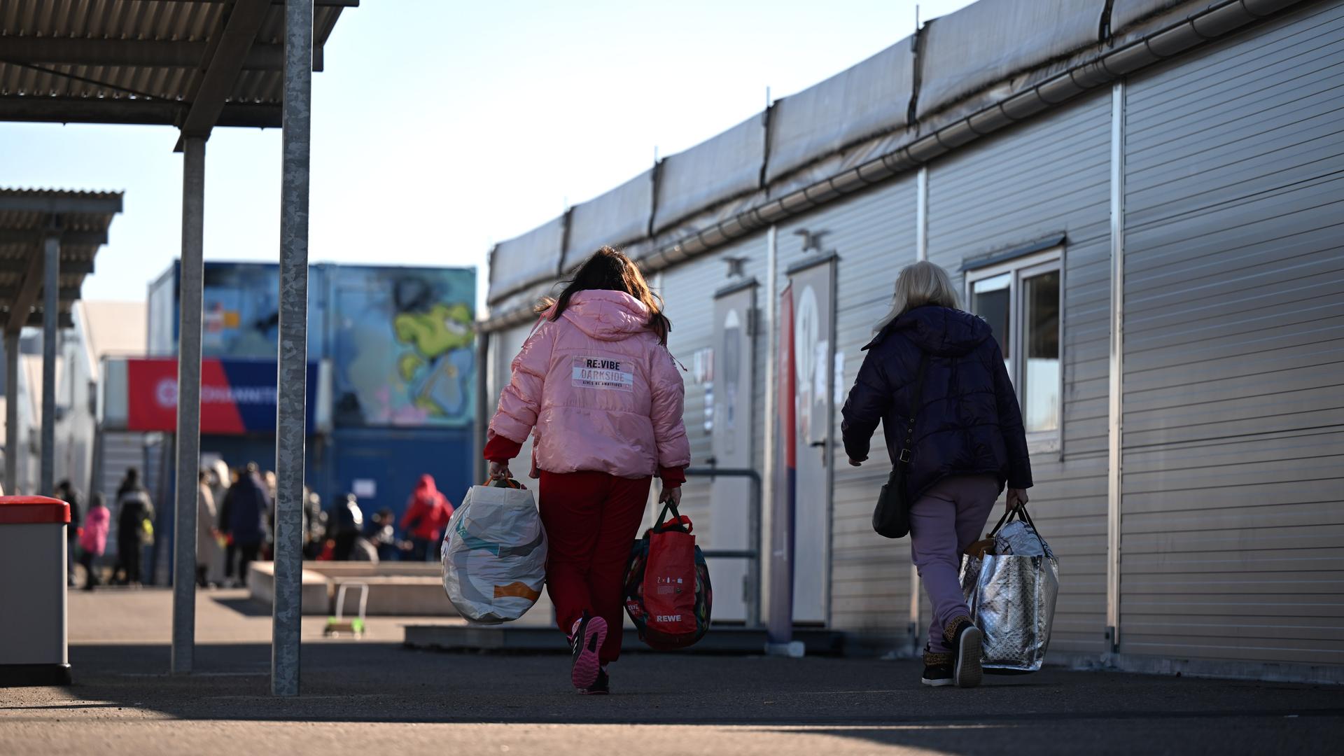 Mit Gepäck gehen zwei Frauen aus der Ukraine durch eine Aufnahmeeinrichtung für Geflüchtete in Leipzig. Mit Gepäck gehen zwei Frauen aus der Ukraine durch eine Aufnahmeeinrichtung für Geflüchtete in Leipzig.