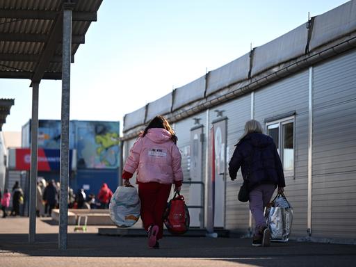 Mit Gepäck gehen zwei Frauen aus der Ukraine durch eine Aufnahmeeinrichtung für Geflüchtete in Leipzig.