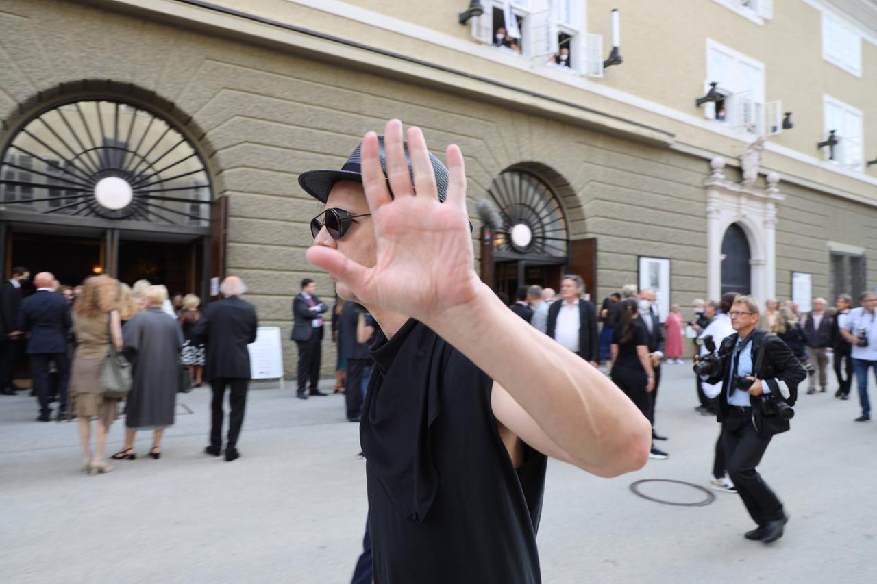 Teodor Currentzis läuft mit erhobener Hand, um sich vor Fotografen zu schützen, zu den Salzburger Festspielen 2021. Teodor Currentzis läuft mit erhobener Hand, um sich vor Fotografen zu schützen, zu den Salzburger Festspielen 2021.