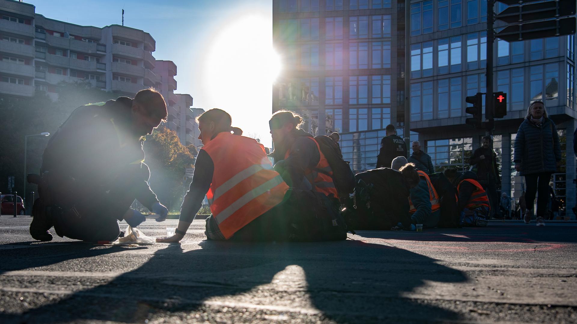 Straßenblockade in Berlin: Verschiede Personen sitzen auf dem Boden. 