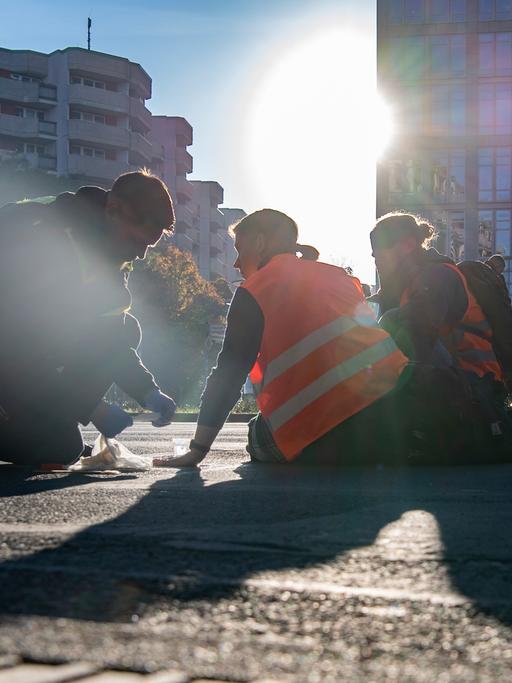 Straßenblockade in Berlin: Verschiede Personen sitzen auf dem Boden. 