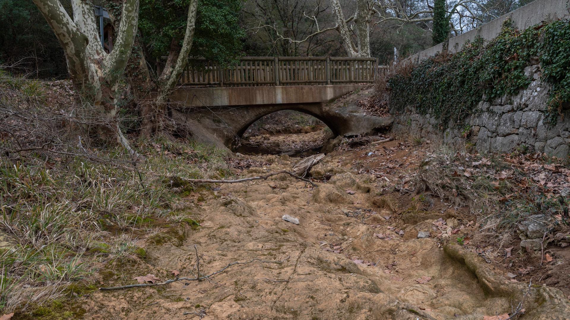 Eine Brücke führt über ein ausgetrocknetes Flussbett. 