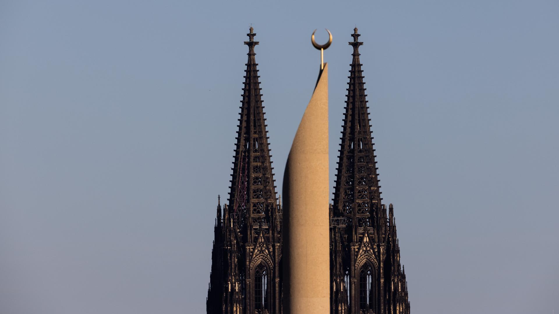 Im Licht in der untergehenden Sonne ist ein Minarett der Zentralmoschee der DITIB (Türkisch-Islamische Union der Anstalt für Religion) und der Kölner Dom zu sehen. Im Licht in der untergehenden Sonne ist ein Minarett der Zentralmoschee der DITIB (Türkisch-Islamische Union der Anstalt für Religion) und der Kölner Dom zu sehen.