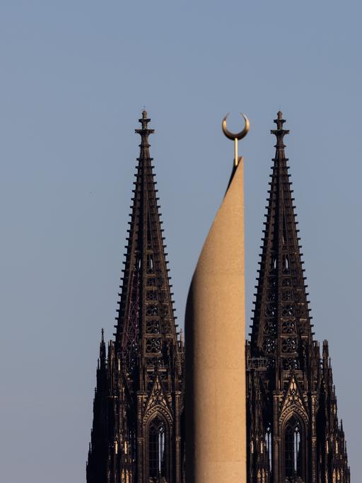Im Licht in der untergehenden Sonne ist ein Minarett der Zentralmoschee der DITIB (Türkisch-Islamische Union der Anstalt für Religion) und der Kölner Dom zu sehen.