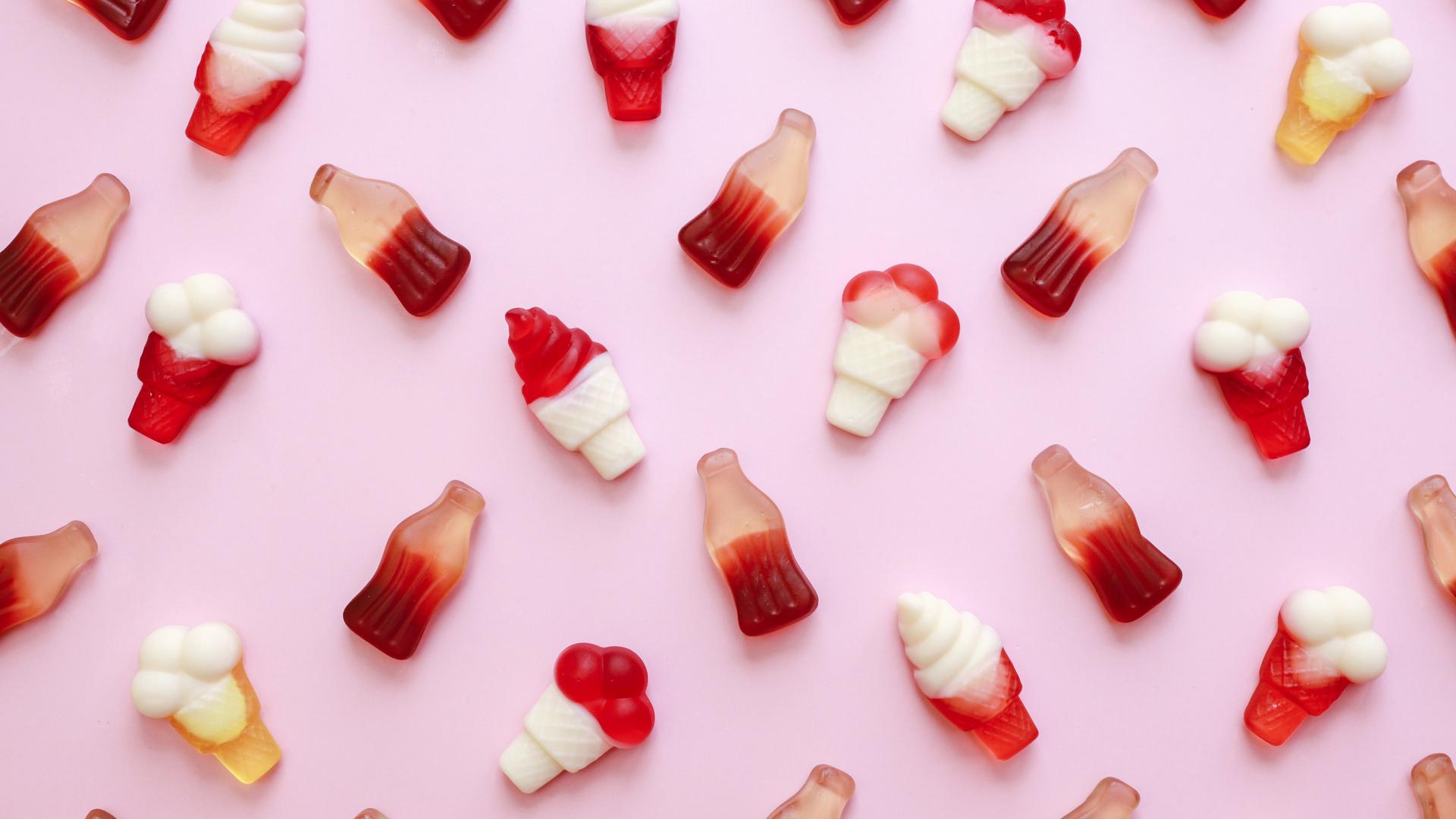 Naschgummis in Form von Eiscreme und Colafläschchen auf rosa Hintergrund. Naschgummis in Form von Eiscreme und Colafläschchen auf rosa Hintergrund.